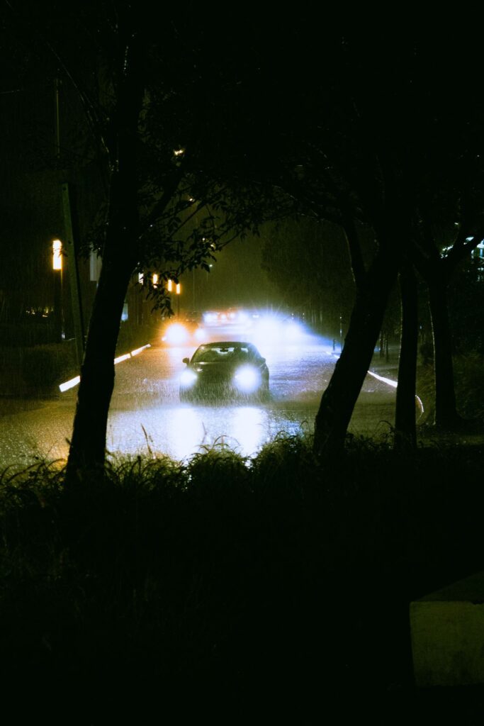 Car headlights cutting through heavy rain at night on a UK road - 24/7 accident recovery conditions